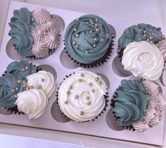 six cupcakes with white and blue frosting in a box