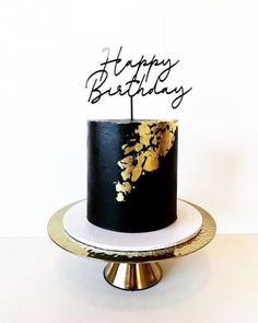 a black and gold birthday cake sitting on top of a white plate with the words happy birthday written on it