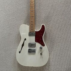 a white electric guitar sitting on top of a carpet