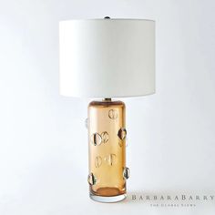 a glass table lamp with a white shade on it