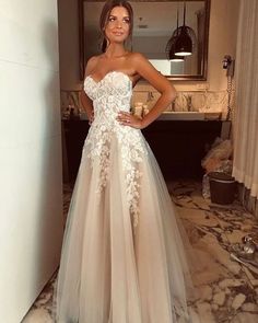 a woman standing in a room wearing a dress with flowers on the boudle