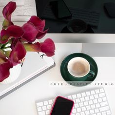 a cup of coffee sitting on top of a desk next to a keyboard and phone