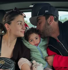 a man, woman and child are sitting in the back seat of a car together