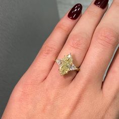 a woman's hand with a yellow diamond ring on it