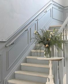 a vase filled with flowers sitting on top of a table next to a stair case