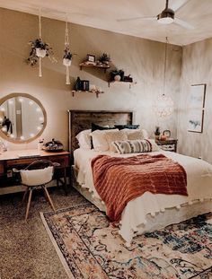 a bedroom with a bed, desk and mirror on the wall next to an area rug