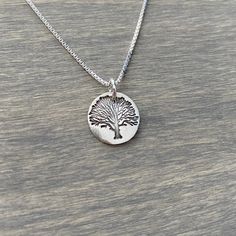 A little tree stamped into a fine silver disc. The pendant measures about 5/8 inches diameter. It comes with a sterling silver box chain. Symbolic Silver Tree Of Life Jewelry, Silver Tree Of Life Necklace For Healing, Yellow Gold Sterling Silver Tree Of Life Necklace, Tree Of Life Necklace Silver, Sterling Silver Tree Of Life Necklace With Round Pendant, Tree Stamp, Kraft Gift Boxes, Tree Necklace, Silver Box