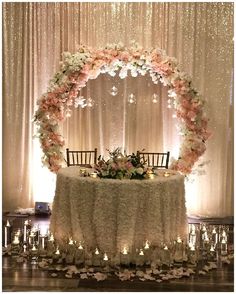 a table with flowers and candles on it in front of a curtained backdrop at a wedding