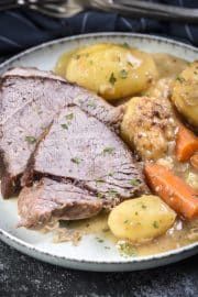 a plate with meat, potatoes and carrots on it