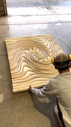 a man sitting on the ground next to a piece of wood