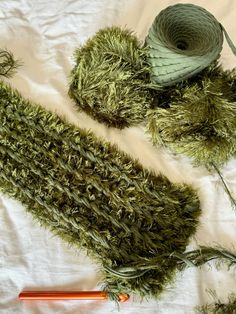 yarn and needles laid out on top of a sheet of cloth with grass growing from it