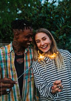 two people standing next to each other holding sparklers