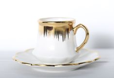 a white and gold coffee cup on a saucer