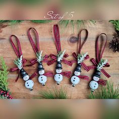 six snowman ornament ornaments are arranged on a wooden surface with pine cones and evergreen branches