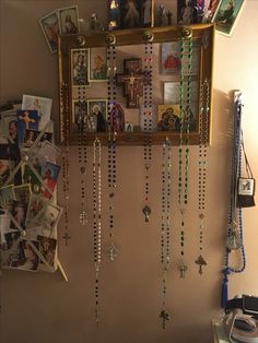 a wall with pictures and beads hanging from it's sides next to a mirror