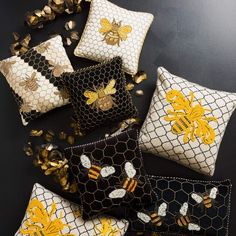 several decorative pillows with bees and honeycombs on them, sitting on a black surface