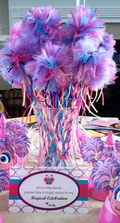 there are some pink and blue decorations on the table with purple flowers in vases