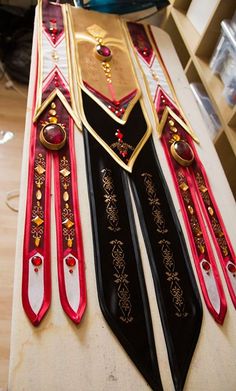 two black and red ties with gold trims on top of a wooden table in a room