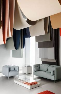 a living room filled with furniture and lots of hanging material on the ceiling above it