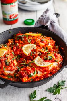 a skillet filled with red sauce and lemon slices