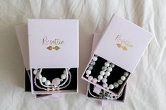 two boxes with necklaces in them sitting on a bed