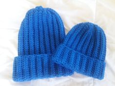 two blue knitted hats laying on top of a bed