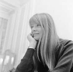 a woman with long hair sitting at a table in front of a mirror and looking off to the side