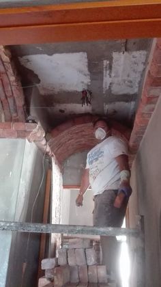 a man standing in the middle of a room with bricks on the floor and walls