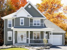 a brown house with white trim and two garages on the front, surrounded by fall foliage