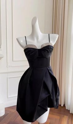 a mannequin wearing a black dress on top of a wooden floor