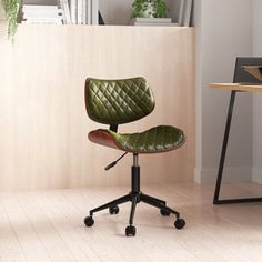 a green office chair sitting on top of a wooden floor in front of a desk