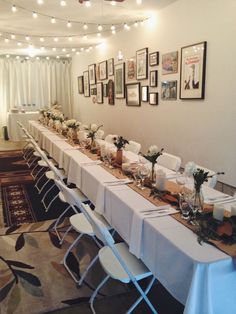 a long table is set up with white linens and place settings for an event