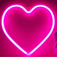 a heart shaped neon sign in the middle of a dark room with a pink background