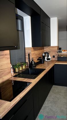 a kitchen with black cabinets and wooden counter tops is seen in this image from the front view