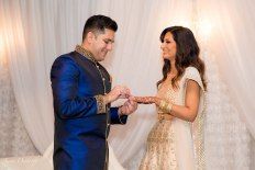 a man and woman standing next to each other in front of a white curtain holding hands