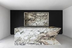 a marble counter top in a room with black walls and white flooring, along with a painting on the wall