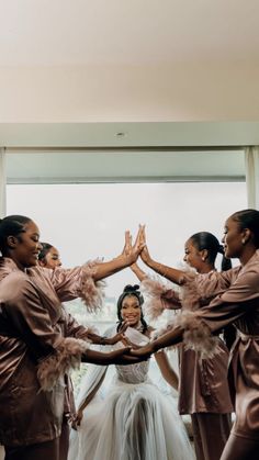 a group of women standing next to each other in front of a window with their hands together