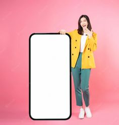 a woman in yellow jacket and green pants holding up a white sign on pink background