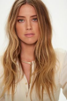 a woman with long blonde hair wearing a collared shirt and gold choker necklace