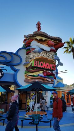 people are walking past a giant hamburger sign