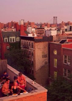 some people are sitting on top of a building and having dinner together in the city