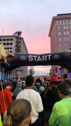 a group of people standing under an inflatable sign at the start of a race