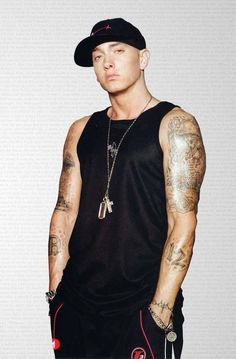 a man with tattoos on his arms and chest wearing a baseball cap, black tank top and red shorts