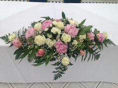 a bouquet of pink and white flowers sitting on top of a tablecloth covered table