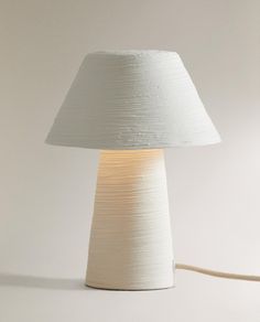 a lamp that is on top of a white surface with a cord attached to it