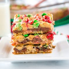 three pieces of candy bar on a white plate with a glass of milk in the background