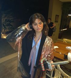 a woman wearing headphones and raincoat standing next to a table