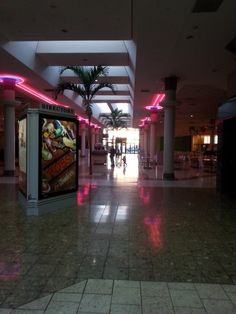 an empty shopping mall with people walking around the area and palm trees in the background