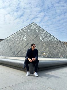 a man sitting on top of a cement bench next to a pyramid