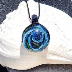 This stunning Galaxy Pendant is handmade with borosilicate glass, making each piece truly unique, like a work of art. Crafted with care, this one-of-a-kind pendant features a circular design inside, created with pure silver and gold fuming. When heated, these metals work their magic, transforming into beautiful colors that shift from white to shades of blue, with touches of orange and green, creating a galaxy-like effect.                               Peace, love, and pendants, baby! ✌️💚🌊 The Artistic Clear Jewelry For Gifts, Artistic Round Glass Jewelry, Iridescent Glass Jewelry As Gift, Iridescent Glass Jewelry Gift, Modern Handmade Murano Glass Jewelry, Round Recycled Glass Necklaces For Gifts, Iridescent Glass Jewelry For Gifts, Multicolor Recycled Glass Jewelry As A Gift, Multicolor Recycled Glass Jewelry For Gifts